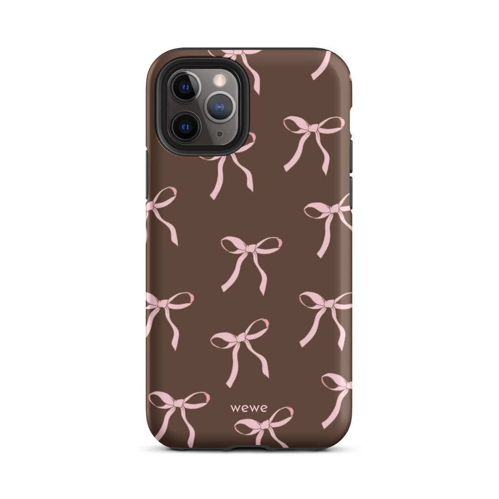 Custom iPhone 11 pro tough case in matte dark brown (chocolate) featuring an all-over repeating pattern of light pink ribbons/bows, with 'wewe' branding at the bottom.