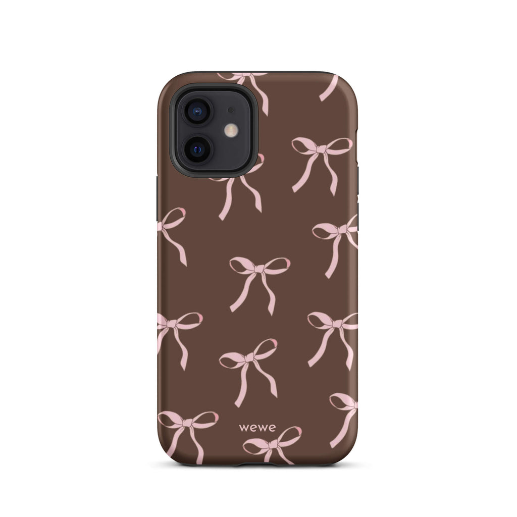 Custom iPhone 12 tough case in matte dark brown (chocolate) featuring an all-over repeating pattern of light pink ribbons/bows, with 'wewe' branding at the bottom.