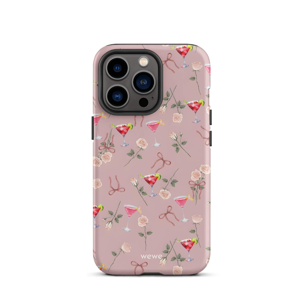 Custom iPhone case 13 pro with a repeating pattern of pink roses, ribbon bows, and red cocktail glasses on a light rose colour background.