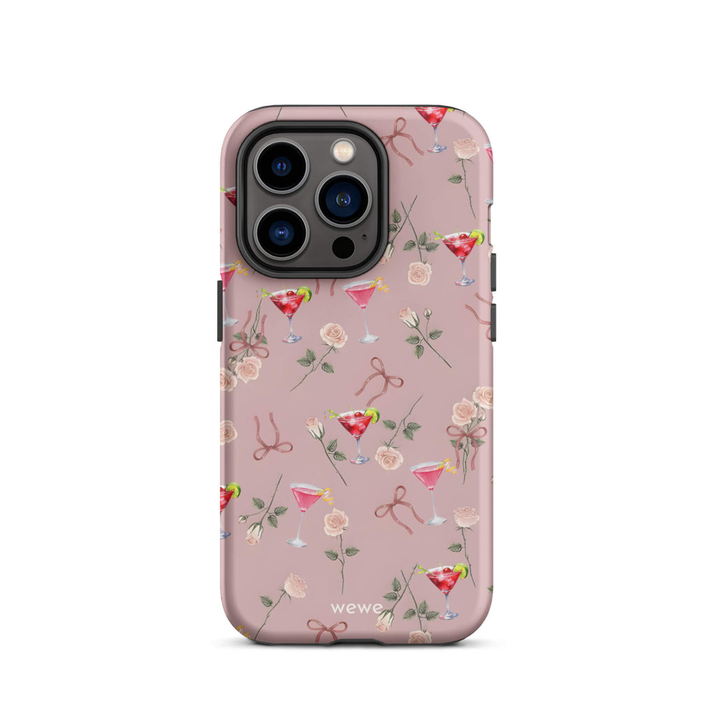 Custom iPhone case 14 pro with a repeating pattern of pink roses, ribbon bows, and red cocktail glasses on a light rose colour background.