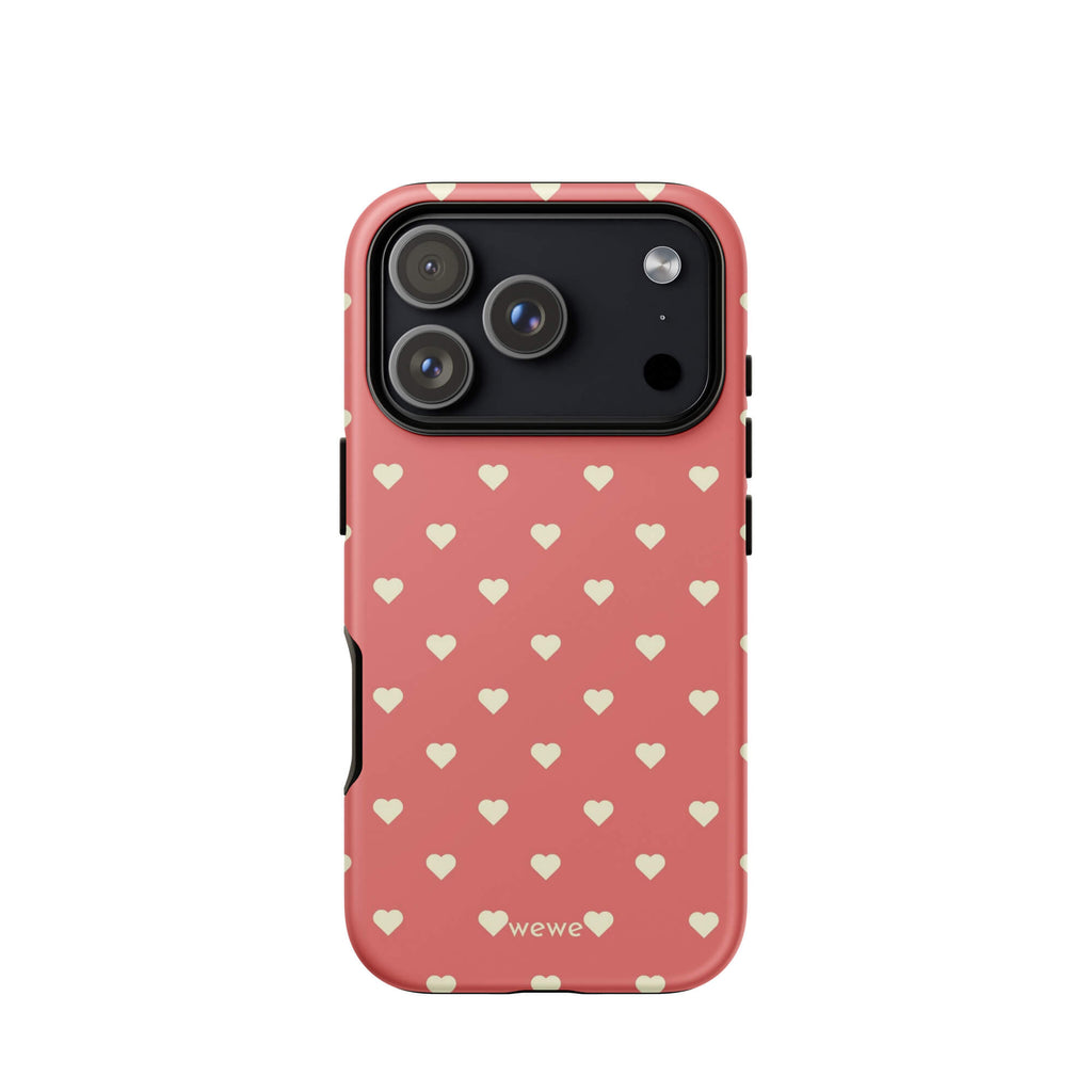 Coral-pink iPhone case with evenly spaced soft-cream mini hearts