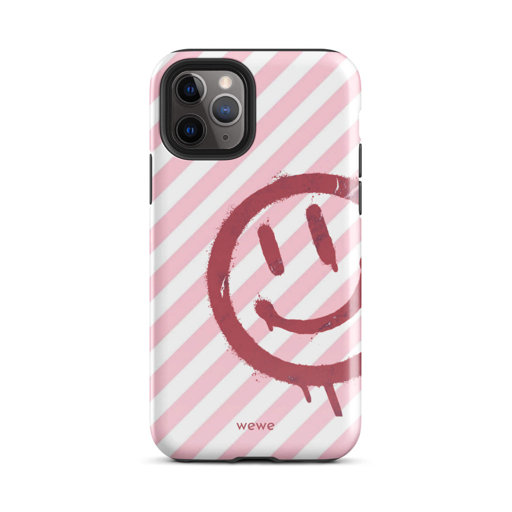 Custom iPhone case 11 pro with a pink and white diagonal stripe background and a red spray paint graffiti smiley face.