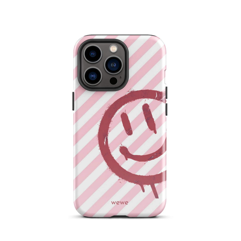 Custom iPhone case 13 pro with a pink and white diagonal stripe background and a red spray paint graffiti smiley face.