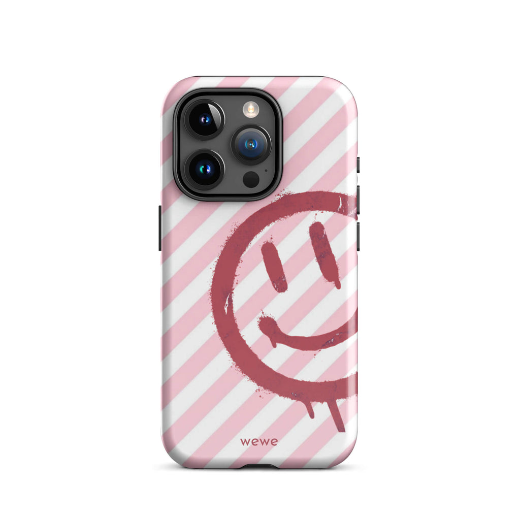 Custom iPhone case 15 pro with a pink and white diagonal stripe background and a red spray paint graffiti smiley face.